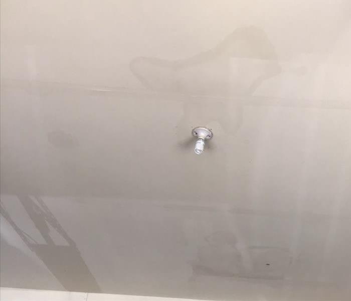 white ceiling with water spots and a single lightbulb