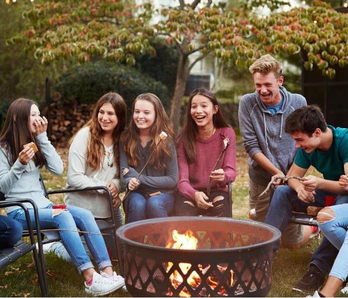 Kids laughing and enjoying smores around a fire pit.